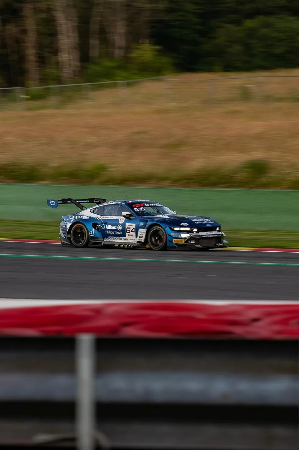 Voiture de course bleue saisie en filé le long des vibreurs rouges et blancs