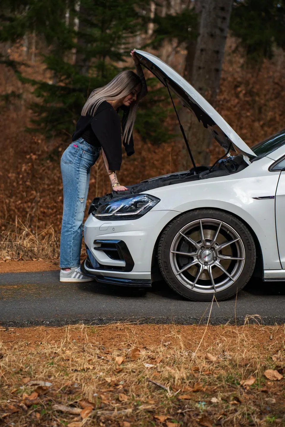 Personne penchée sur le moteur d'une Volkswagen Golf R blanche capot ouvert