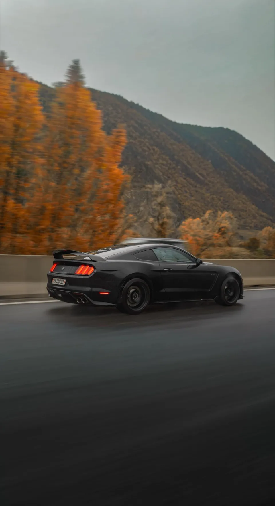 Ford Mustang Shelby GT350 noire en roulage de profil, décor de montagne en filé